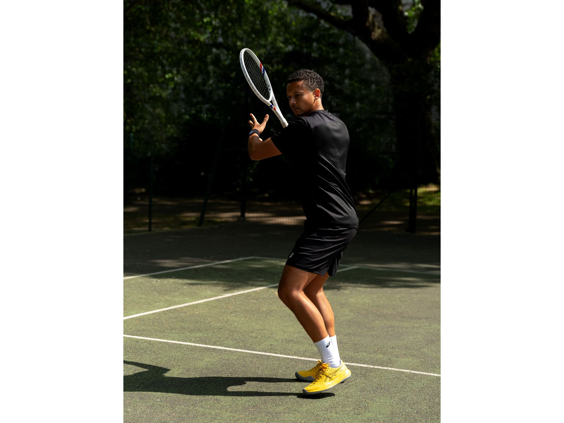 A player preparing a backhand in yellow ASICS GEL-CHALLENGER 15 shoes